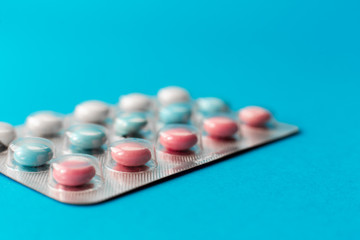 sealed blister of colored pills on a blue background. Medical concept