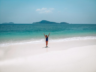 Good-looking girl in a blue swimming suit raising her hands to the sky and enjoying picturesque view.