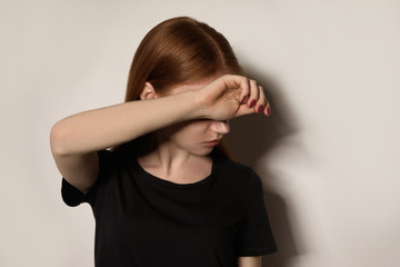Fototapeta premium Young woman covering face against light background