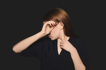 Upset young woman crying against dark background