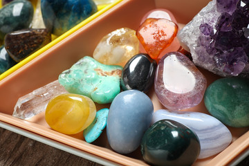 Plastic tray with different beautiful gemstones on table
