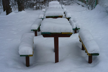 Cold snow-white Russian winter. Snow covered tables and benches in picnic area in the natural parkland. The concepts of beauty of nature and ecological tourism.