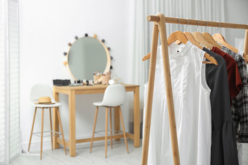 Hangers with stylish clothes on rack in makeup room. Space for text