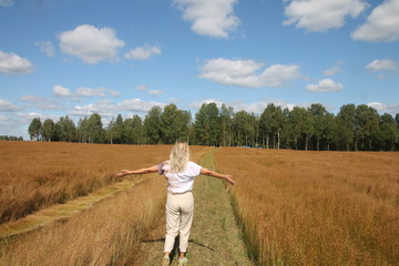 A young girl stands on a field where flax is being harvested