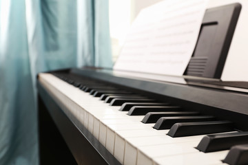Fototapeta na wymiar Modern piano with music sheets in room, closeup