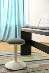 Stool and modern piano with music sheets in room