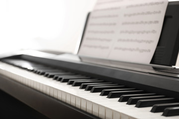 Fototapeta na wymiar Modern piano with music sheets in room, closeup