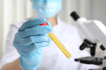 Doctor holding test tube with urine sample for analysis in laboratory, closeup