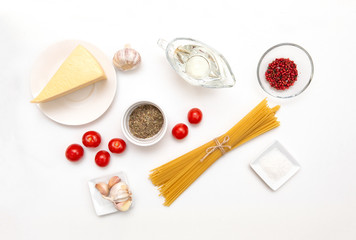 pasta, spaghetti,  oil in a gravy boat, a piece of cheese, garlic, tomatoes, spices on a white background, top view,