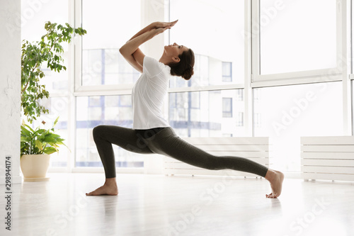 Fototapete Young Woman Practicing Crescent Lunge Pose With Eagle Arms In Yoga Studio New Africa