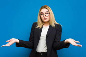 young pretty blonde woman raising palm to forehead thinking oops, after making a stupid mistake or...