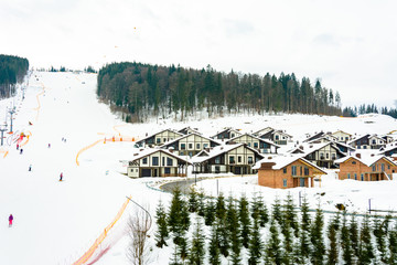 Lift and ski slope with skiers below it on a sunny winter day with blue sky, ski resort Bukovel.