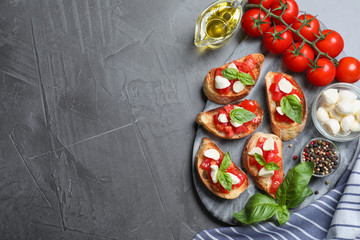 Delicious bruschettas with cheese and tomatoes on grey table, flat lay. Space for text
