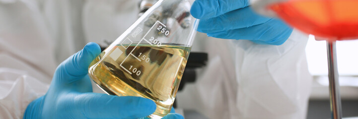 Male chemist look at microscope hold test tube