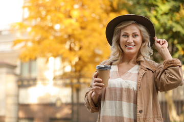 Beautiful mature woman with cup of coffee outdoors