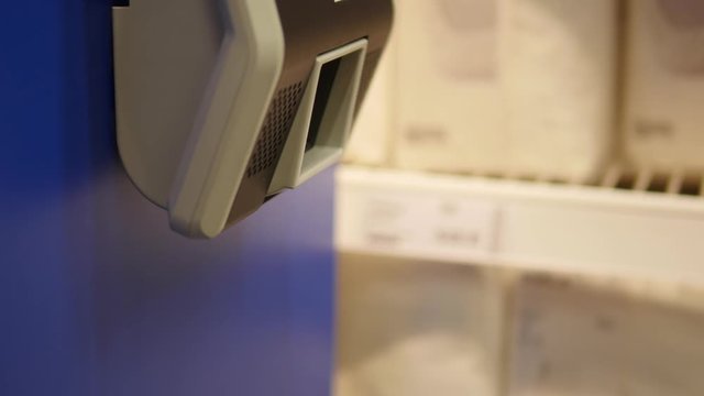 Movement of a woman holding goods in her hands to check prices on a barcode scanner in a store