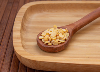 View of pigeon pea also known as toor dal in a wooden spoon. Isolated on wooden plate.