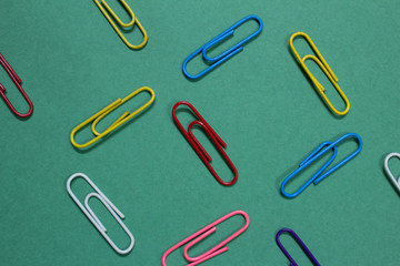 Colourful paperclips on a green colour background