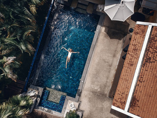 Aerial view of the territory of the Thai hotel: tiled terracotta roofs, palm trees, the pool with...