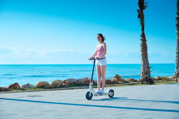 Young woman with electric scooter on a sea coast © Oleg