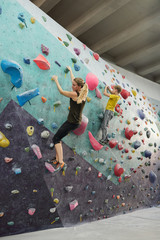 Active woman and her son in sportswear climbing wall with small artificial rocks