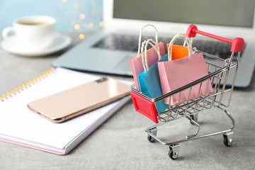 Composition with small shopping cart and paper bags on grey background, space for text © Atlas