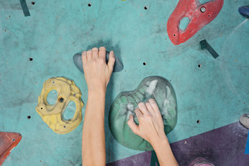 Hands of young sportswoman grabbing by artificial rocks