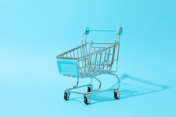 Small shopping cart on blue background, space for text