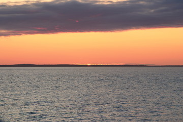 Image of the sun setting in the sea behind the island