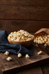 Delicious popcorn with caramel on wooden background..