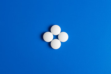 four white round pills on a blue background