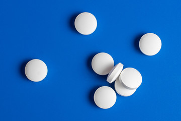 white round pills scattered blue background, chaotically scattered.