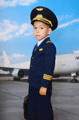 4 years old boy in a pilot suit posing before the plane