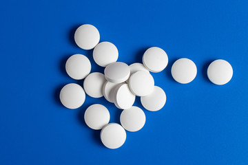 white round pills scattered blue background, chaotically scattered.