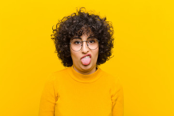 young pretty afro woman feeling disgusted and irritated, sticking tongue out, disliking something...