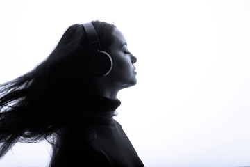 Beautiful woman with flowing hair in headphones listening music. White background.