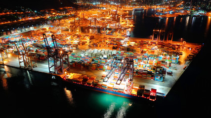 Aerial night shot of illuminated industrial cargo truck size container terminal in Perama and Drapetsona commercial port near Piraeus, Attica, Greece