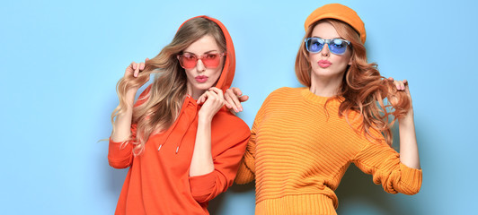 Fashionable woman in stylish outfit, makeup having fun dance. Two happy blonde redhead tomboy girl, trendy orange jumper, hoody, fashion hair. Cheerful sister friend, funny colorful concept