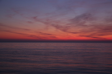 Beautiful red sunset on the sea. Bright colors of sunset are reflected in the water.