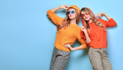Two easy-going happy hipster Woman smiling in Stylish fashion orange colored outfit. Beautiful Girl...