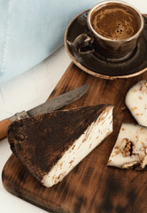 Top view. A piece of sliced homemade (craft) goat cheese with walnut. Near a cup with espresso on a wooden board. Grey background. Dessert concept.