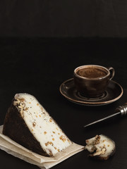 A slice of fresh sliced homemade (craft) goat cheese with walnut closeup. On the back black background is an espresso cup. Dessert concept.