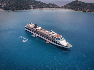 Bird eye view of the amazing white cruise ship sailing by the islands, blue ocean, horizon; luxurious tour concept.