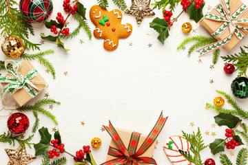 Christmas background with gingerbread cookies, gift boxes and branches of holly with red berries on white. Winter festive nature concept. Flat lay, copy space.