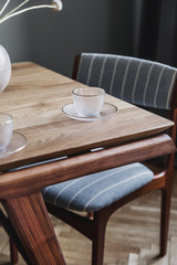 Stylish and modern dining room interior with design sharing table, chairs, glamour decoration and elegant accessories. Flowers in vase.  Template. Interior design. Home decor. 