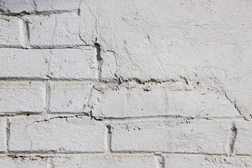 Texture of a brick wall coated with white paint and partially covered with plasterwork