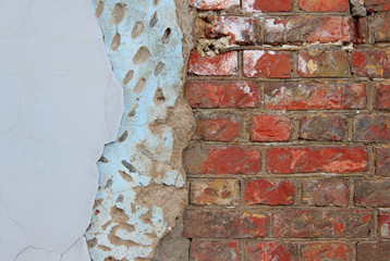 An old damaged brick wall partially covered with two layers of plasterwork