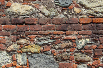 Wall made of natural rocks, bricks and scrap bricks 