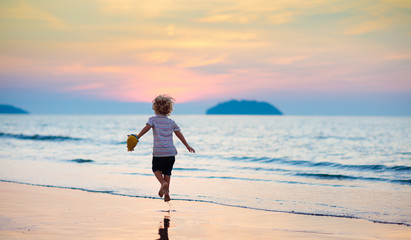 Child playing on ocean beach. Kid at sunset sea.