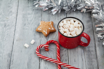 Red mag of drink with candy cane and Christmas gigerbread on wooden background. Top View.